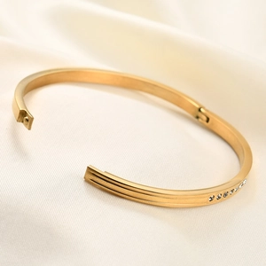 18K gold-plated stainless steel hinge bangle with cubic zirconia on beige silk