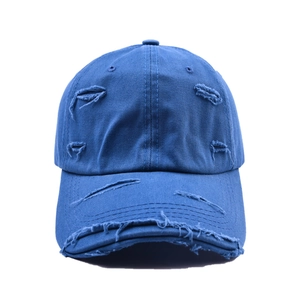 Détail des trous usés et des bords effilochés sur la casquette de baseball vintage en coton bleu