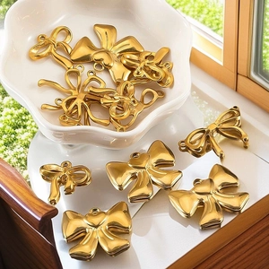 Macro shot of gold bow-shaped metal pendants for DIY jewelry making displayed on a tray