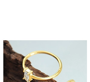 Close-up of minimalist gold ring with a rectangular zircon stone on natural wood base