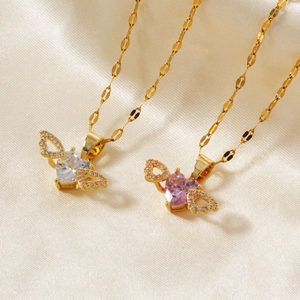 Detail of heart-shaped zircon necklaces with angel wings on silk background