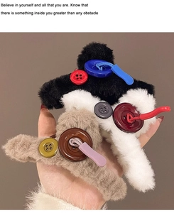 Detail of plush hair claw clips in black, white, and khaki with decorative buttons