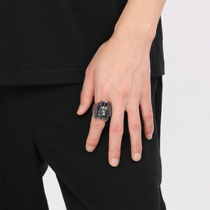 Detailed macro view of vintage silver Anubis embossed ring on person's finger