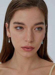 Close-up of gold plated hoop earrings with light blue resin drops and clear zircon accents
