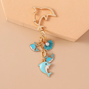 Detailed view of dolphin and shell charms on a gold metal keychain with blue enamel