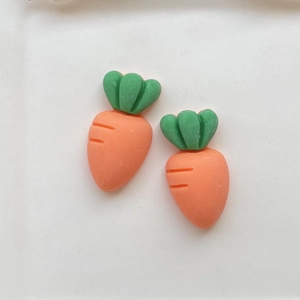 Flat lay of two vibrant resin carrot charms for DIY crafts on a clean white background