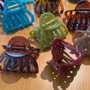 Close-up of elegant French pumpkin-style hair claws in multiple colors on a wood surface