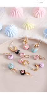 Detail view of heart-shaped gold earrings with colorful enamel and inlaid zircons
