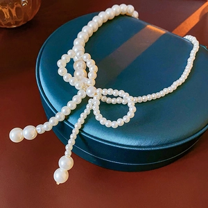 Dettaglio della collana di perle annodata a fiocco su un portagioie verde scuro