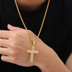 Macro detail of men's gold stainless steel cross necklace with silver cracked texture