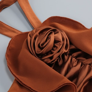 Detailed macro view of 3D satin rose applique and ruffled edges on a brown formal dress