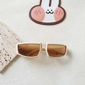 Detail view of cream rectangle Y2K sports sunglasses with orange lenses on a textured stone base