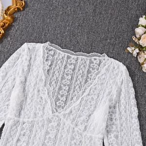 Detailed close-up of intricate white lace floral texture on the long-sleeved V-neck top