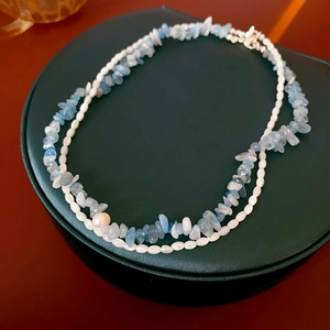 Détail d'un collier double épaisseur avec pierres bleu clair, perles et perle rose