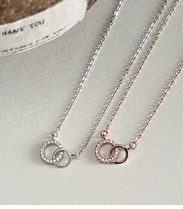Close-up of interlocking double loop necklaces in silver and rose gold with pavé crystals