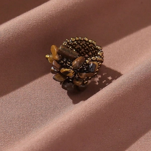 Detailed shot of irregular natural stone beads and woven bronze metal ring texture