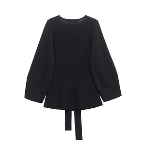 Detail of knit sweater with peplum hem and elegant back ties on white background