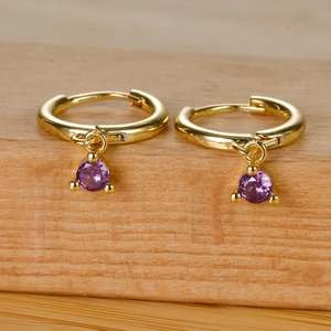 Close-up of golden hoop earrings featuring a vibrant purple round zircon drop charm