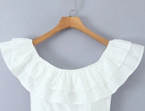 Detail of white off-shoulder top featuring double-layered ruffled neckline and cotton fabric