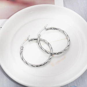 Close-up of silver-tone twisted hoop earrings with a metallic polished finish