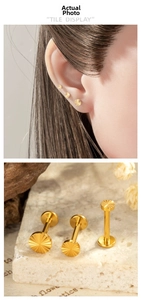 Macro shot of gold titanium sunburst push-pin labret studs in three different sizes