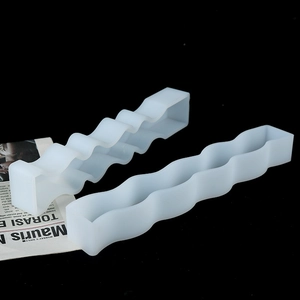 Macro shot of two flexible wavy silicone molds for DIY candle making on a black background