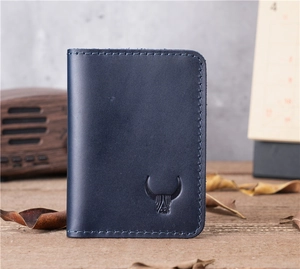 Detailed macro view of deep blue genuine leather card holder with cow logo and stitching