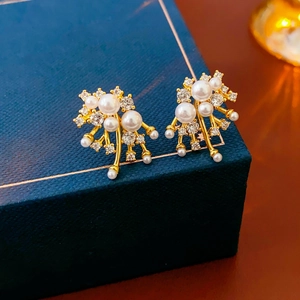 Close-up of gold-plated firework pearl earrings with sparkling crystals in a gift box