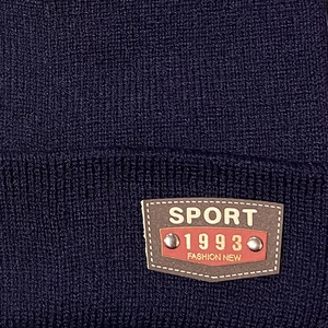 Macro shot of navy knit beanie featuring a brown faux-leather sport logo patch detail