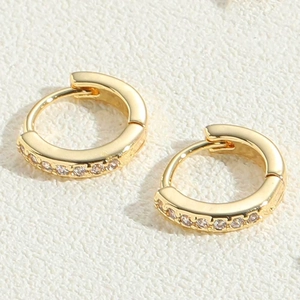 Macro shot of gold hoop earrings featuring fine white cubic zirconia and hinged closure