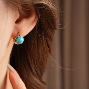 Gros plan d'une boucle d'oreille vintage dorée avec une pierre turquoise incrustée