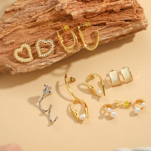 Detailed display of vintage heart pearls and geometric gold earrings on rustic wood blocks