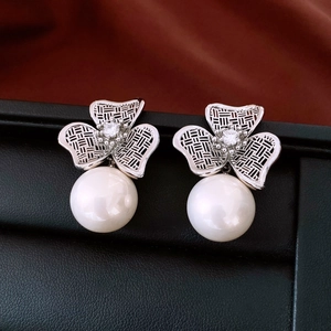 Macro detail of silver flower earrings with hollow grid petals and white pearl drops