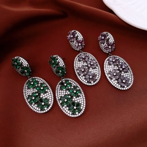Close-up of vintage floral oval drop earrings with green and purple zircon on silk