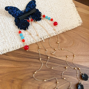 Détail de la pince à cheveux papillon bleu marine avec des glands dorés et perles