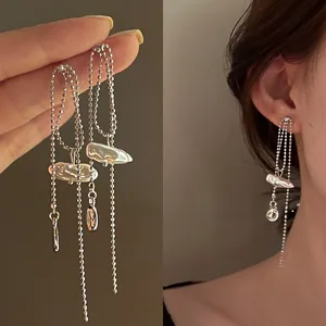 Close-up of long tassel earrings with baroque pearls and silver ball chains