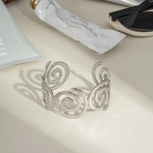 Artistic detail of silver spiral link open cuff bracelet styled with lifestyle props