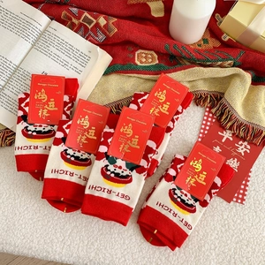 Close-up of four festive red and white New Year socks with cartoon motifs and lucky tags