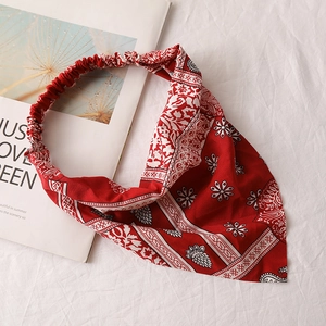 Detail of red ethnic print chiffon hair scarf with elastic band on a white texture background
