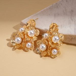 Detail of 18K gold-plated floral earrings with textured petals and inlaid pearls