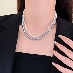Detail shot of a double-layered necklace with white and grey pearls worn by a model