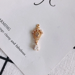 Macro shot of 18K gold plated hollow crown pendant with teardrop zircon on white card