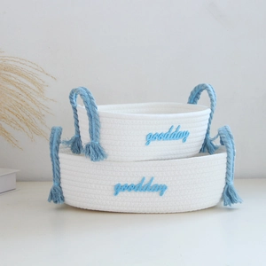 Set of two white handmade cotton rope storage baskets with blue 'goodday' embroidery