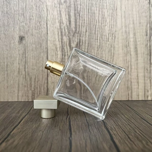 Detailed close-up of a square glass perfume bottle with a golden spray head and golden cap