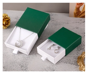 Macro view of dark green drawer jewelry boxes with white lining on marble surface
