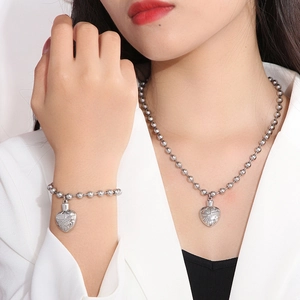 Model wearing a silver heart urn necklace and bracelet set with detailed floral relief