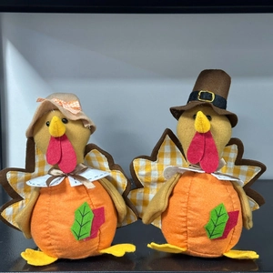Close-up of two felt turkey gnome plushies with pumpkin and maple leaf details for Thanksgiving