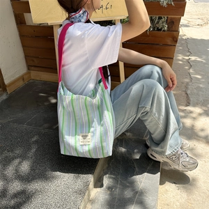 Gros plan d'un sac cabas en toile rayée avec le détail d'une bandoulière rose vif