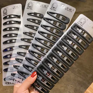 Set of 10 large matte black BB hair clips for women on a display card held by hand