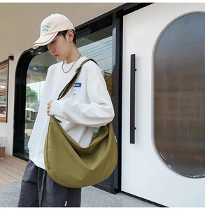 Olive green crescent oxford fabric crossbody bag shown on model in urban setting